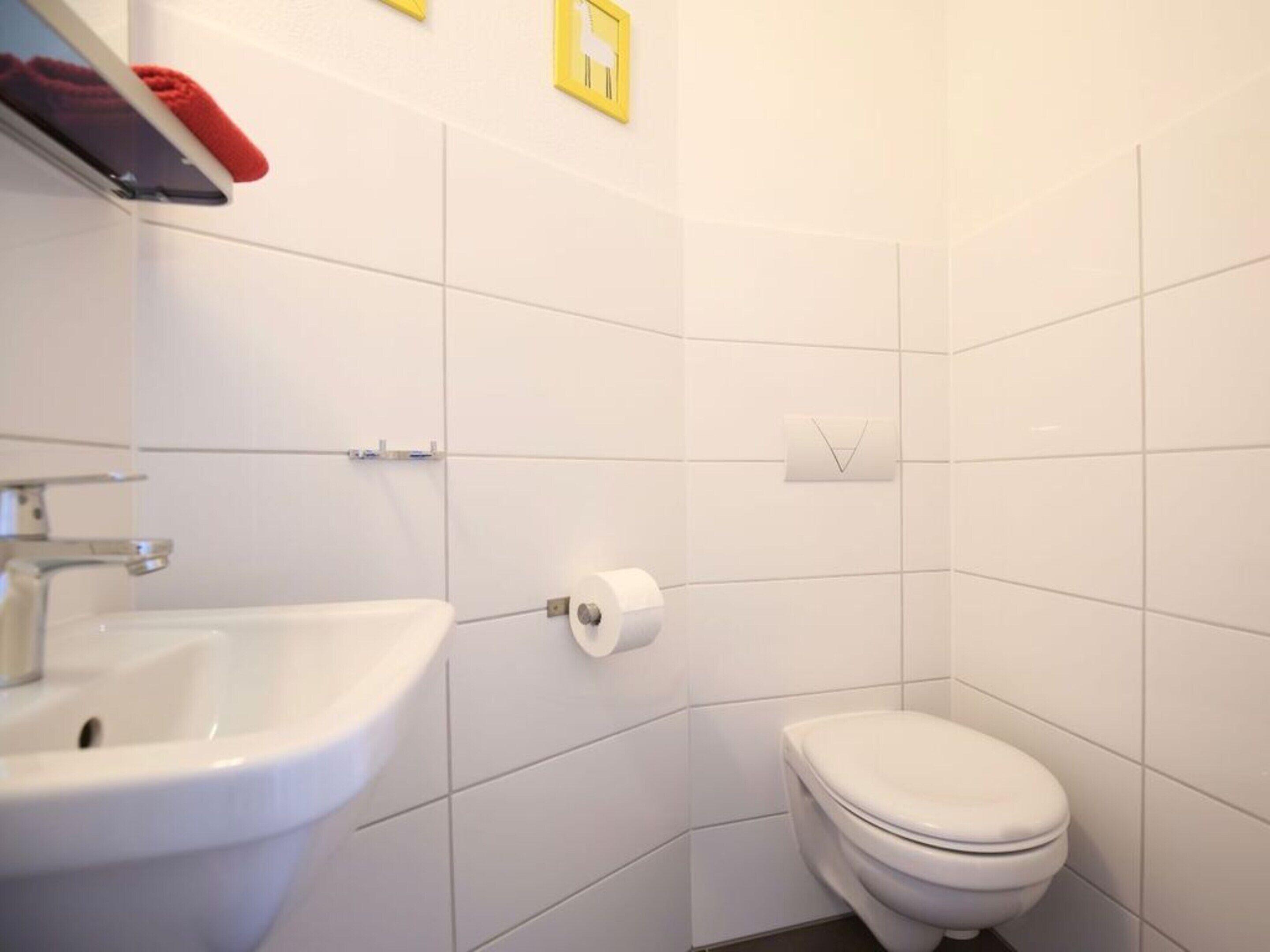A bathroom with a white sink, toilet, and tiled walls.