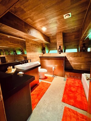 Un baño moderno con detalles de madera, un lavamanos, inodoro y bañera.