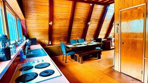 Una cocina con estufa, lavabo y comedor con sillas y mesa.