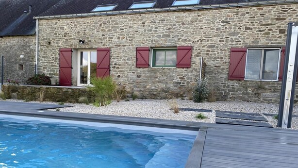 Un edificio de piedra con piscina y terraza de madera.
