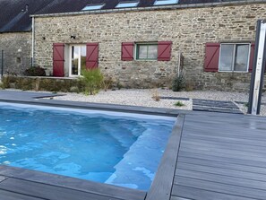 Un edificio de piedra con piscina y terraza de madera.