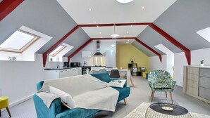 Amplio apartamento tipo loft con cocina, comedor y una sala de estar acogedora con un sofá azul aguamarina y un tapete estampado.
