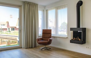 Uma sala de estar moderna com uma grande janela, uma poltrona de couro marrom e uma lareira preta.