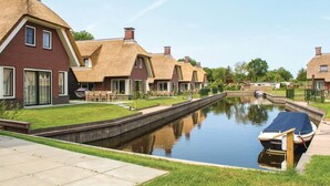 A canal-side residential area with houses, a boat docked, and a narrow waterway. - Villa in Friesland With Waterfront Jetty (Idskenhuizen)