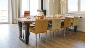 A dining area with a wooden table, six chairs, and a black stove. - Villa in Friesland With Waterfront Jetty (Idskenhuizen)