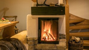A stone fireplace with a wooden mantel, a dining table with chairs, and a wicker basket on the floor. - Carl-lambrecht-chalet No. 19 (Ilsenburg)