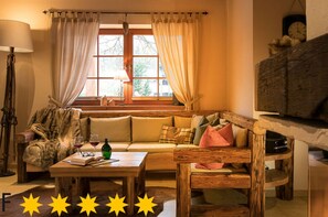 A cozy room with a wooden sofa, a table with a bottle and glasses, and a window with curtains. - Carl-lambrecht-chalet No. 19 (Ilsenburg)