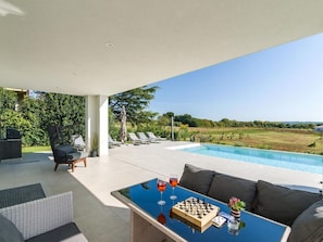 Een modern terras buiten met een zwembad, ligstoelen en een schaakspel.