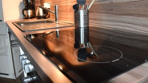 A modern kitchen with a stainless steel sink, a coffee maker, and a utensil holder on the countertop. - Apartment Newport Weser (Bremerhaven)
