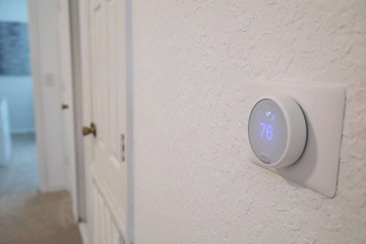 A thermostat displaying a temperature of 76°F on a white wall.