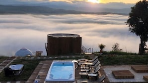 Un jacuzzi, bancos de madera y una estructura de madera con techo en forma de cúpula.