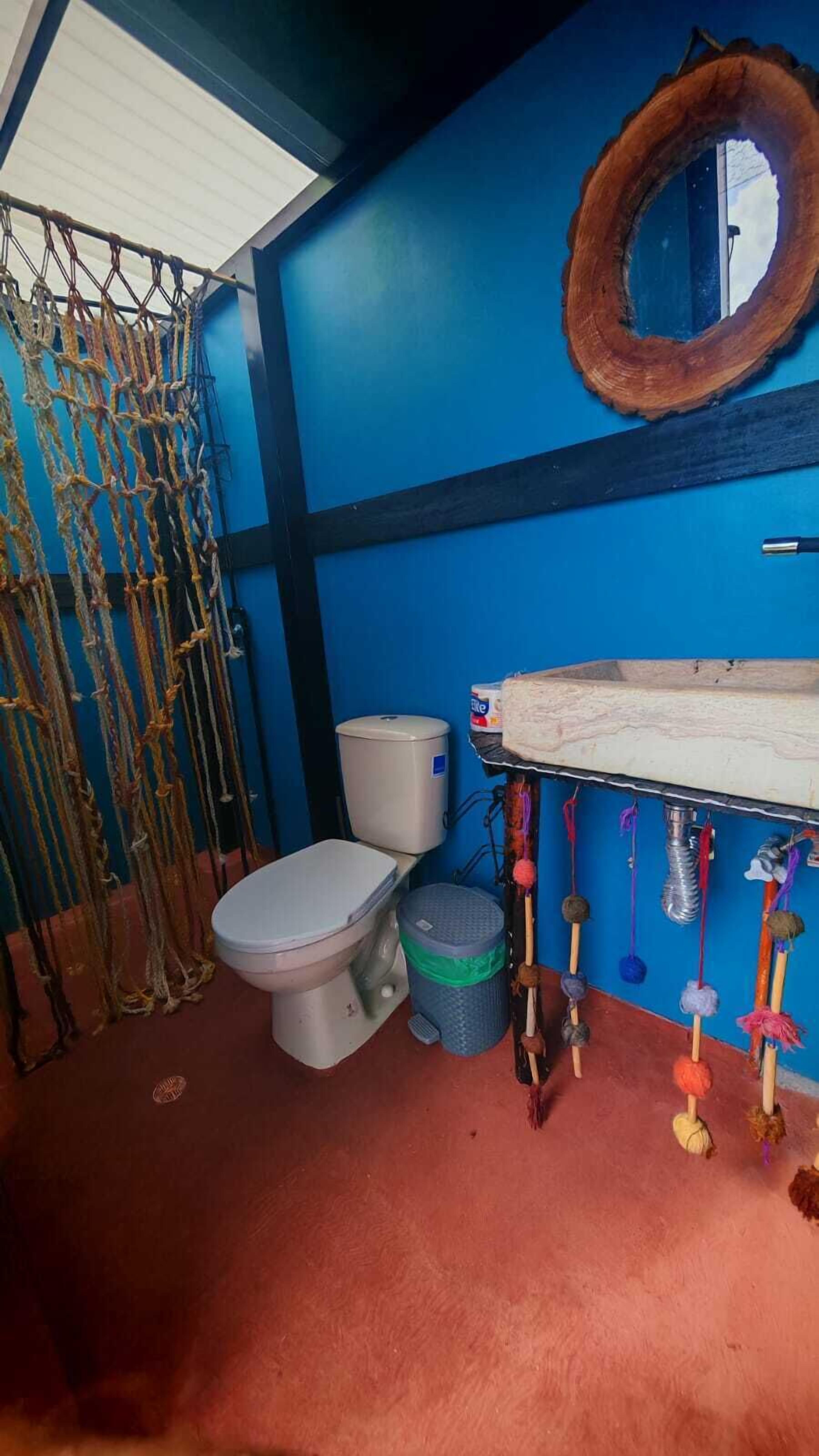 A bathroom with a toilet, a sink, a blue wall, and a wooden ring decoration.
