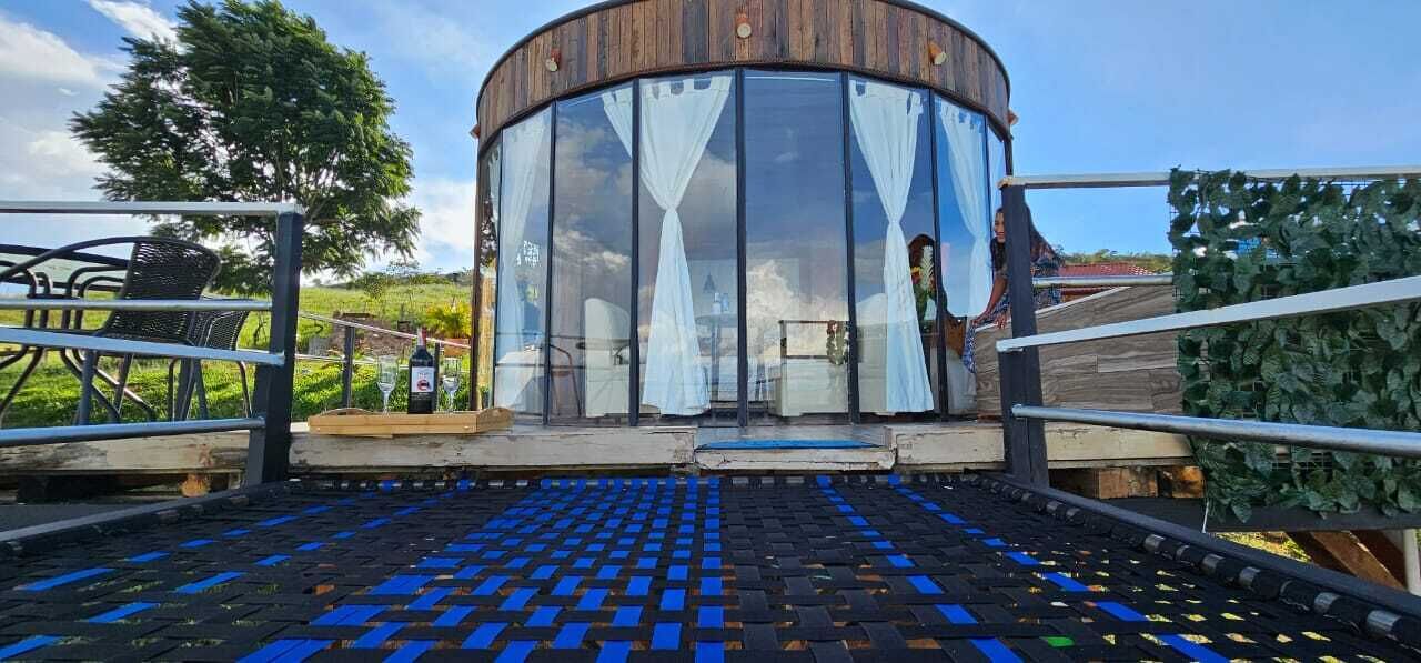Un bâtiment circulaire doté d’une façade en verre, d’une terrasse en bois et d’une rambarde en métal.