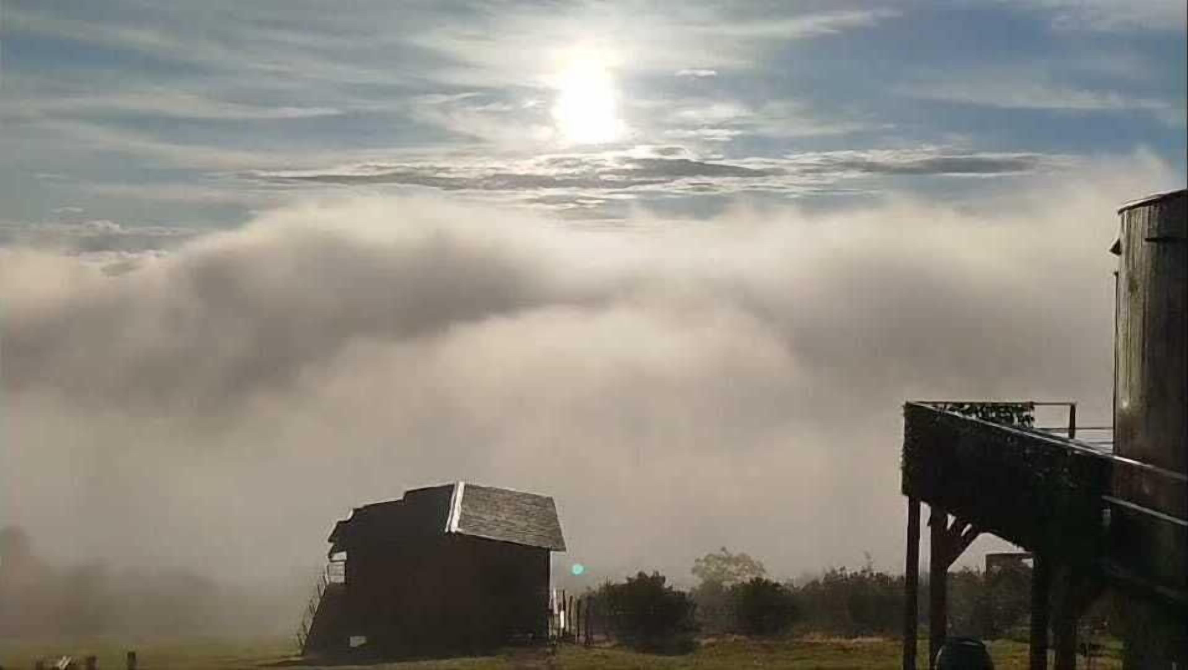 Un paisaje rural con un edificio pequeño y un silo.