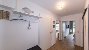 A hallway with wooden flooring, a white wall, a black bench, a fish decoration, and a ceiling light. - High Geest 4 - Including Many Extras (Cuxhaven)