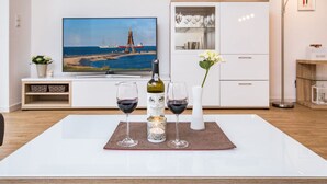 A modern living room with a flat-screen TV, a wine bottle, and glasses on a table. - High Geest 4 - Including Many Extras (Cuxhaven)