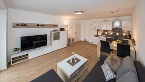 A modern living room with a flat-screen TV, a coffee table, and a sofa. - High Geest 4 - Including Many Extras (Cuxhaven)