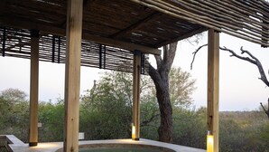 A hot tub under a wooden pergola with stone walls, surrounded by trees. - Villa in Hoedspruit With Hot Tub (Hoedspruit)
