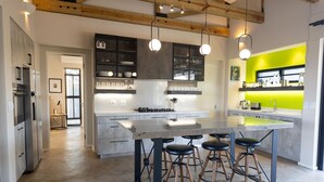 A modern kitchen with a central island, bar stools, and pendant lighting. - Villa in Hoedspruit With Hot Tub (Hoedspruit)