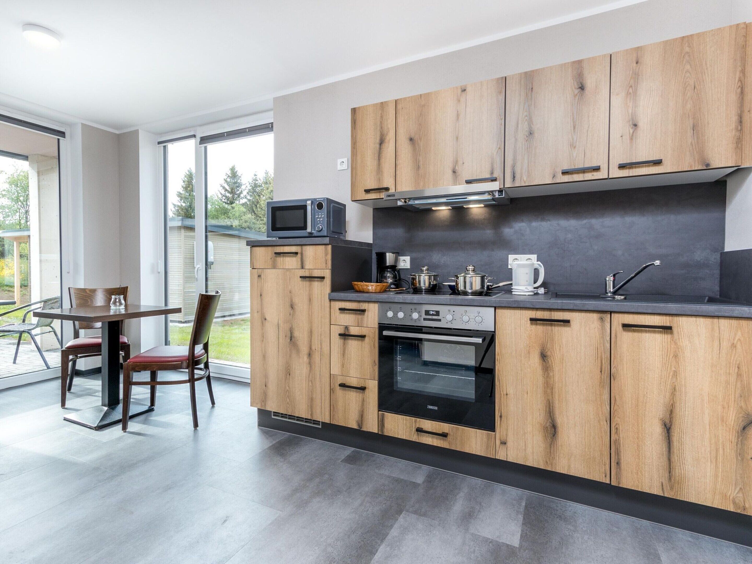 Een moderne keuken met houten kastjes, een ingebouwde magnetron, een fornuis en een spoelbak.