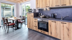 Una cocina moderna con armarios de madera, horno empotrado y comedor con mesa y sillas.
