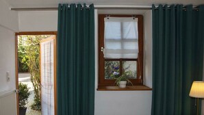 A bedroom with a bed, a window with a view of greenery, and a nightstand with a lamp. - Nice Apartment in Weilmunster (Weilmünster)