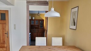 A dining area with a wooden table and white chairs, a pendant light, and a framed picture on the wall. - Nice Apartment in Weilmunster (Weilmünster)