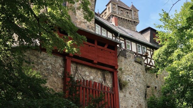 A historic stone building with a red wooden gate and a tower. - Nice Apartment in Weilmunster (Weilmünster)
