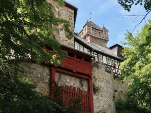 Un bâtiment historique en pierre, doté d’une porte en bois rouge et d’une tour.