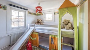 Ein Kinderzimmer mit Stockbetten, einem Spielbereich und einem Fenster.