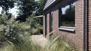 Un edificio moderno con fachada de ladrillo, ventanas grandes y un camino que lleva a la entrada.
