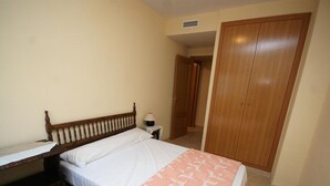 Un dormitorio con una cama de madera, una mesita de noche con lámpara y un armario.