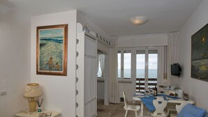 Een kamer met een eethoek, een bank en een schilderij van een strand.