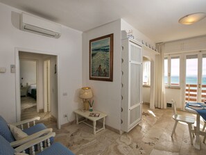 A room with a bed, a table with chairs, a lamp, and a painting on the wall.