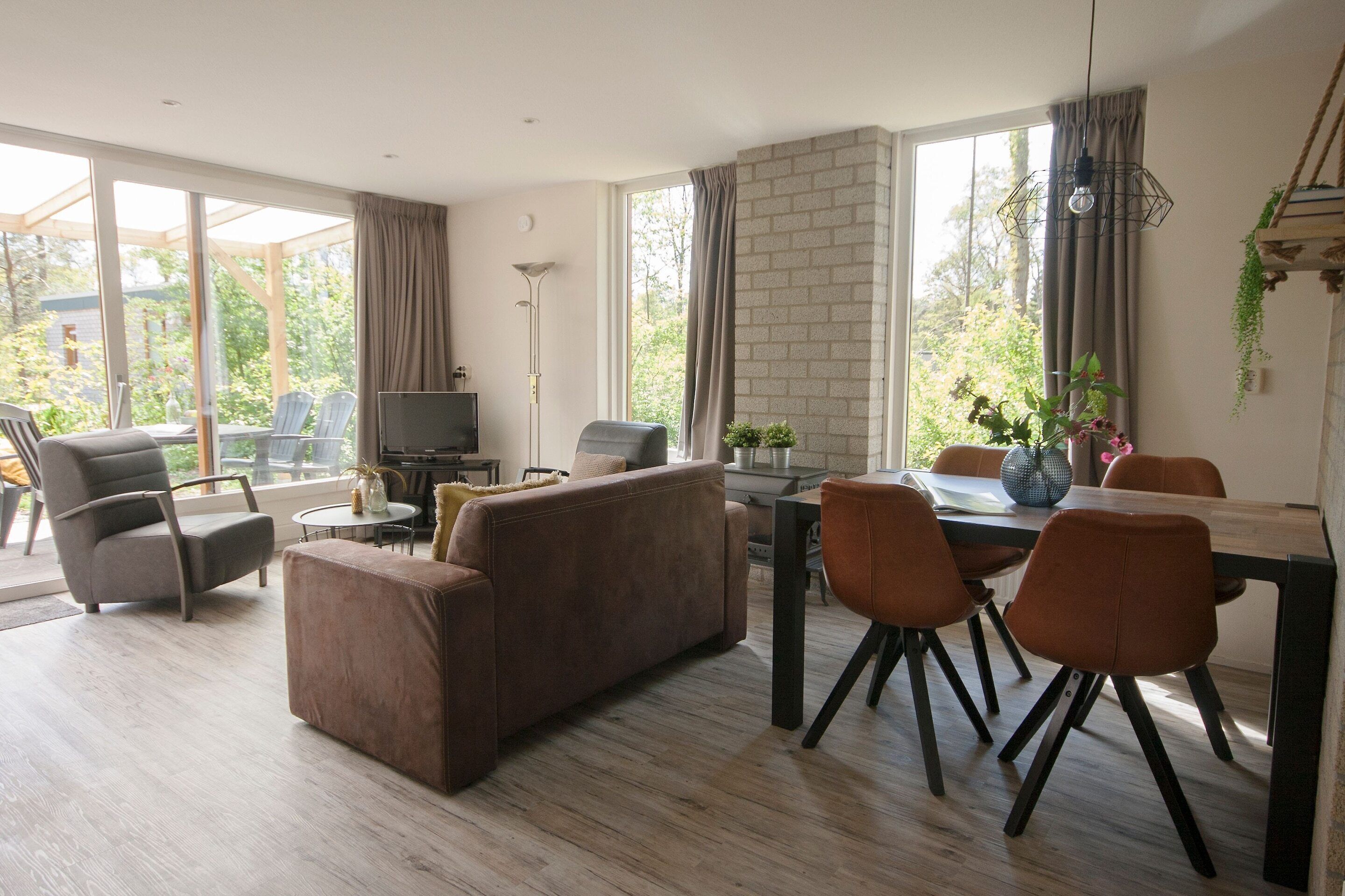 Un salon moderne comprenant un canapé, des fauteuils, une table à manger et un téléviseur.
