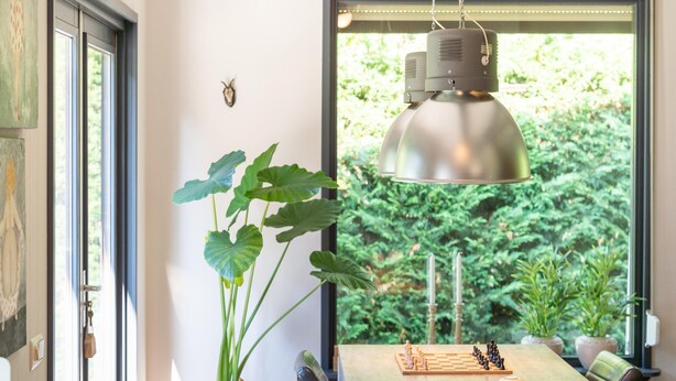 Een eethoek met een houten tafel, een schaakspel en een hangende hanglamp.