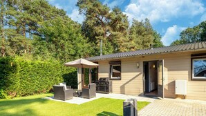 Een huis met een terras, tuinmeubilair en een barbecue.