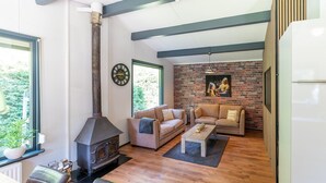 Een gezellige woonkamer met een open haard, twee banken, een salontafel en een bakstenen muur.