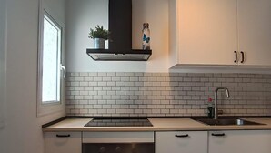 A modern kitchen with white cabinetry, a stainless steel sink, and a built-in oven. - Belvilla by OYO Casa El Pinar (Torremolinos)