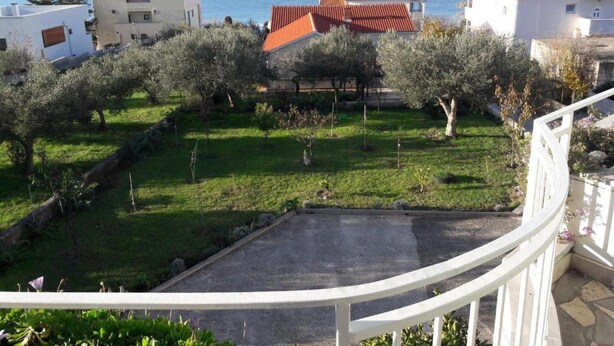 A residential area with a view of the sea, featuring houses with red-tiled roofs, a grassy lawn, and olive trees. - Apartments Kozino - Two Bedroom Apartment (Zadar)