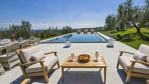 An outdoor pool area with lounge chairs and a table with fruit and candles. - Villa Miniato Comfortable Holiday Residence (San Miniato)