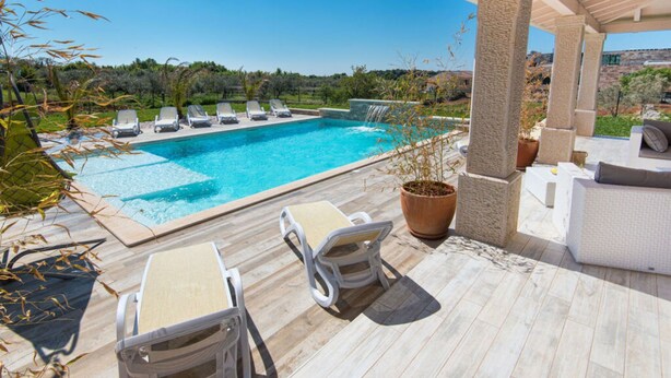 A poolside area with lounge chairs, a table, and a potted plant. - New White Villa, 60 m2, Pool (Vodnjan)