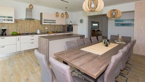 A modern kitchen with a central island, wooden cabinets, and pendant lighting. - New White Villa, 60 m2, Pool (Vodnjan)