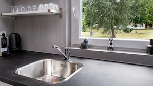 A modern kitchen with a stainless steel sink, a coffee maker, and a window with a view of trees. - Beautiful Holiday Home Near Alkmaar (Hensbroek)
