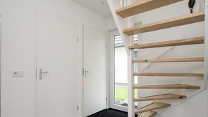 A modern interior with a staircase, white doors, and a black doormat. - Beautiful Holiday Home Near Alkmaar (Hensbroek)