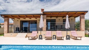 A modern house with a swimming pool, featuring a covered patio with lounge chairs and umbrellas. - Villa Monteci Comfortable Holiday Residence (Vodnjan)