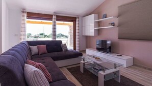 A modern living room with a sectional sofa, a glass coffee table, a flat-screen TV, and built-in shelving. - Villa Monteci Comfortable Holiday Residence (Vodnjan)