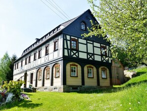 A traditional half-timbered building with a steep gable roof, multiple windows, and a well-maintained garden. - Evening sun Modern Retreat (Cunewalde)