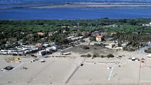An aerial view of a coastal area with a sandy beach, a small town with houses and buildings, and a body of water in the background. - Belvilla by OYO Casa Rosolina Due (Ariano nel Polesine)