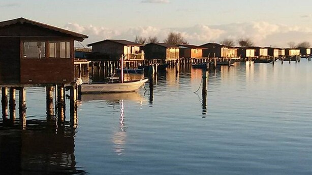 A series of floating wooden structures over calm water, likely used for accommodation. - Belvilla by OYO Casa Rosolina Due (Ariano nel Polesine)